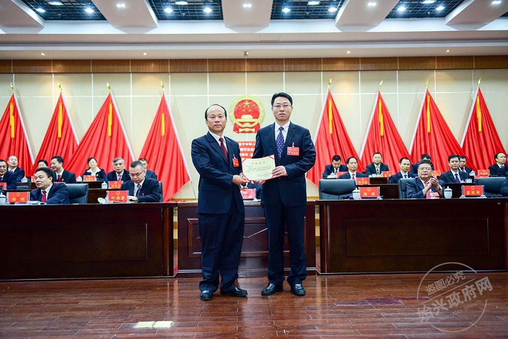李勇當選為始興縣人民政府副縣長，，圖為賴根為李勇右）頒發當選證書